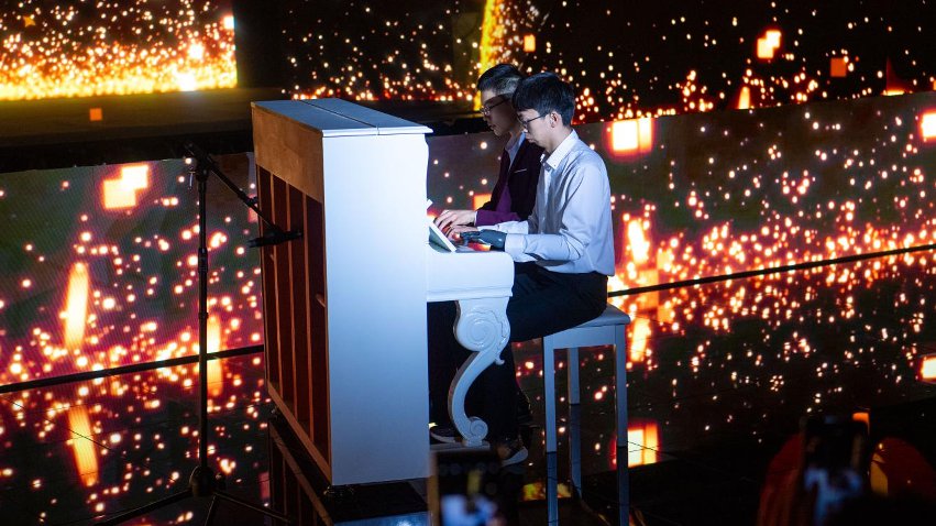 智能仿生手使用者古月與少年鋼琴家舒海峰合奏。主辦方供圖